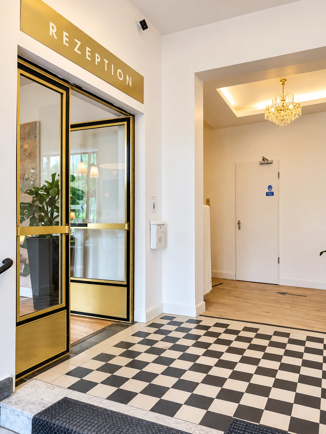 Eingang zur Rezeption des Hotel Bee Fang mit goldener Glastür und Kronleuchter